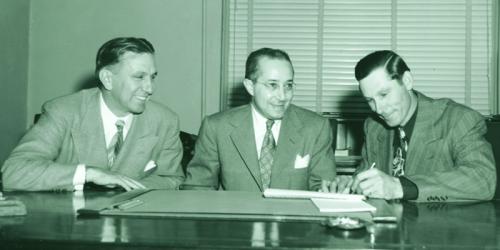 In his first official act as owner of the St. Louis Cardinals, Fred signed left-handed pitcher Harry Breechen (r.) (aka "Harry the Cat"), to a 1949 contract. Manager Eddie Dyer is on the left.